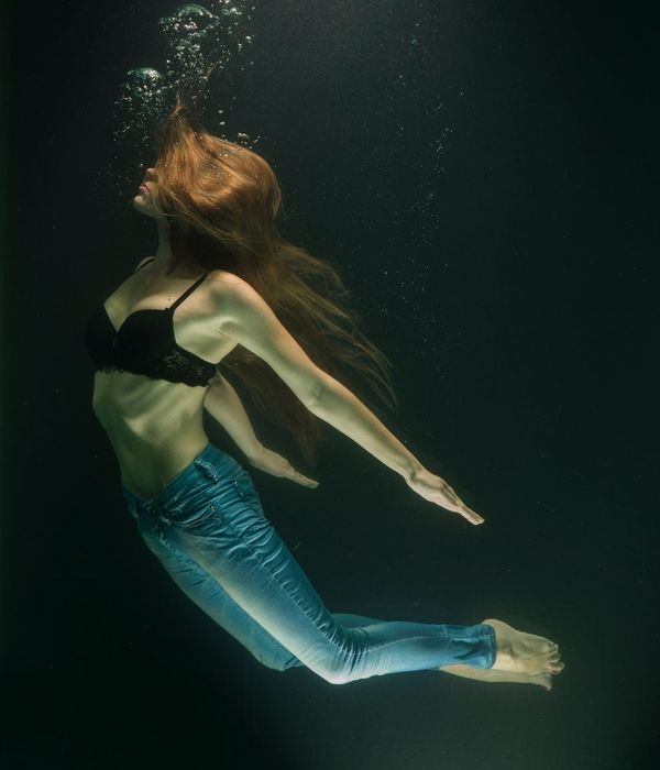 Woman in a dynamic cardio pose against a dark background with light blue accents.